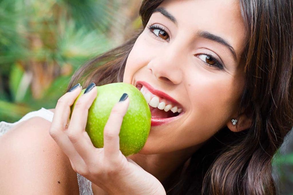 Portrait of a young woman holding a green apple