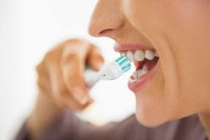 Closeup on happy young woman brushing teeth.