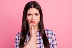 Close-up portrait of straight-haired lady having pain attack teeth damage care oral hygiene isolated over pink pastel background