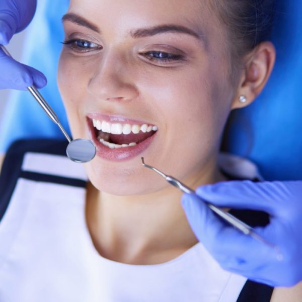 Young Female patient with open mouth examining dental inspection at dentist office